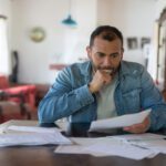 Latin American low income man checking his home finances and looking worried while looking at the utility bills - lifestyle concepts