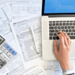 Close up photo of a woman doing taxes with laptop and tax forms in a house