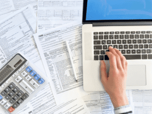 Close up photo of a woman doing taxes with laptop and tax forms in a house